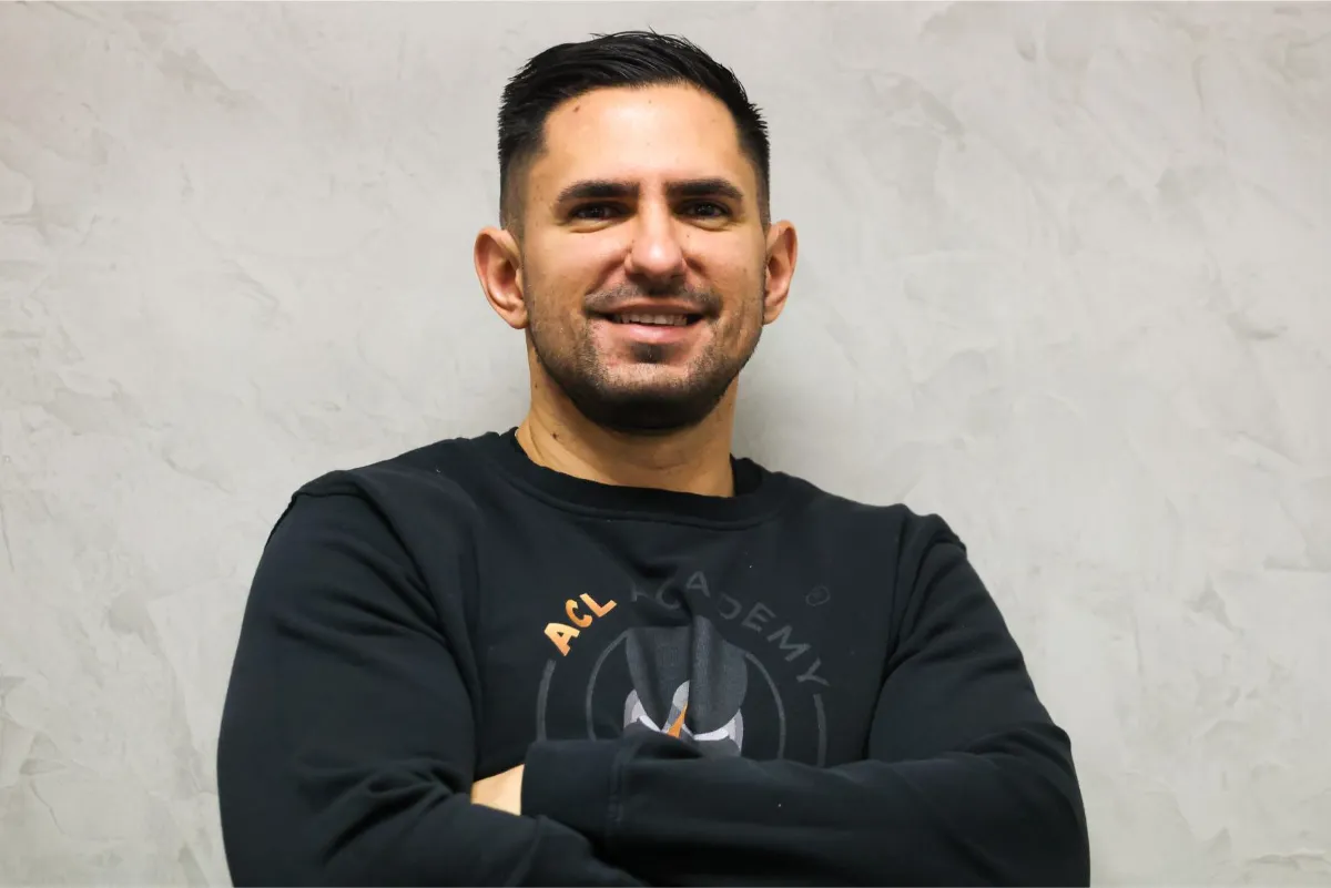 Dr. Kaan Celebi, PT, DPT, arms folded, wearing an ACL Academy sweatshirt